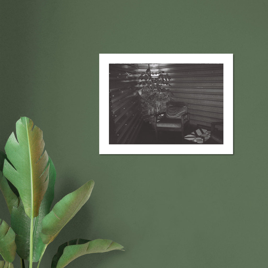 Moody black and white film photo of an empty chair inside a dimly lit room in Mexico City.