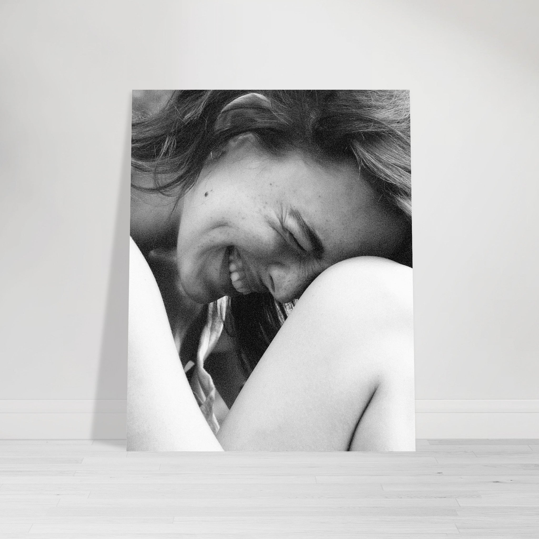 Close-up black and white portrait of a woman smiling with her face resting on her knees