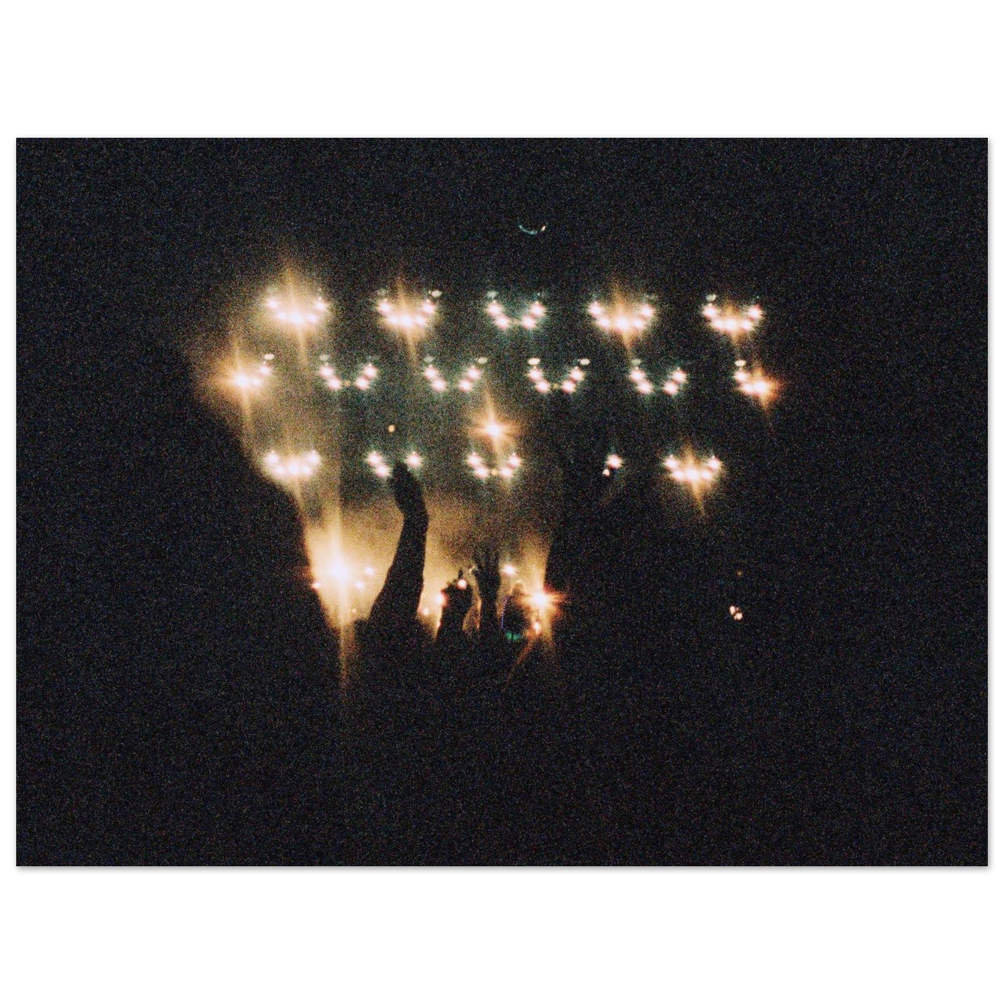 Fireworks display with silhouettes of people against a dark sky
