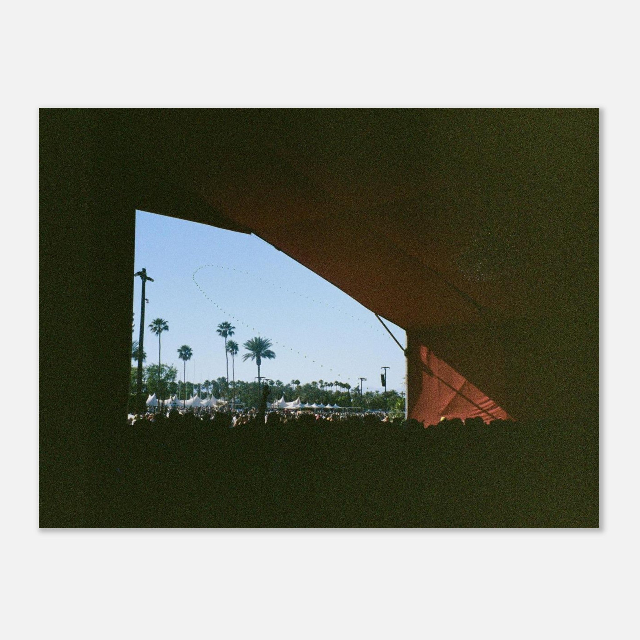 View through a festival stage with palm trees and tents outside
