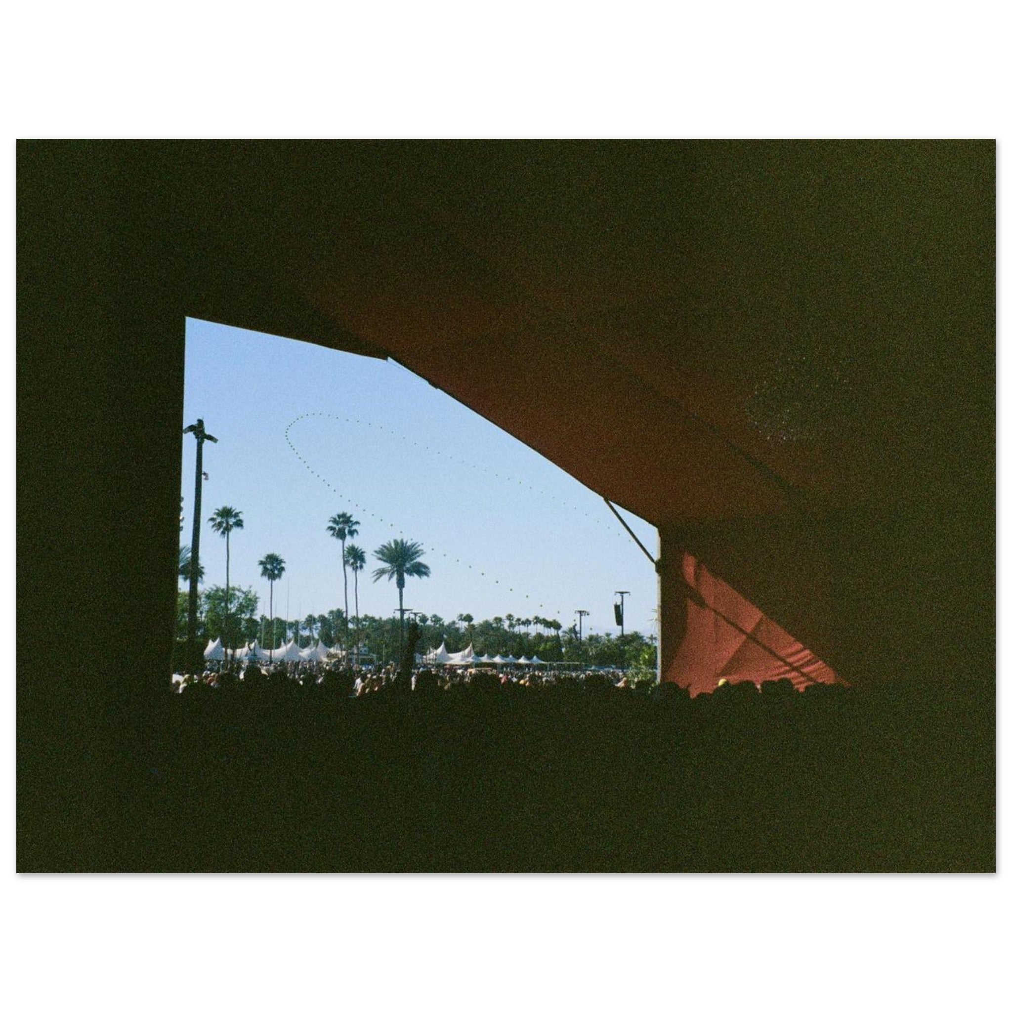 View through a festival stage with palm trees and tents outside