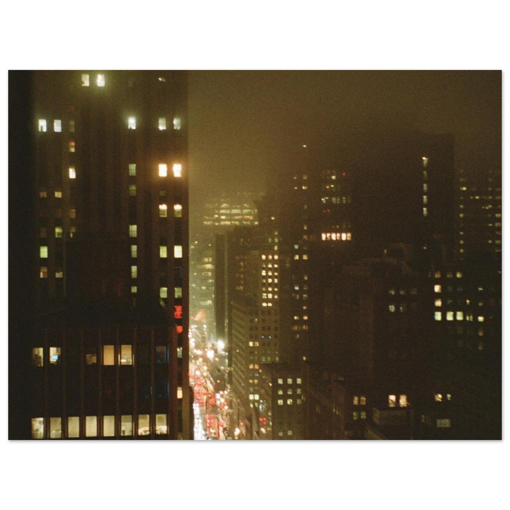 Film photo of wet city buildings at night across dark foggy streets