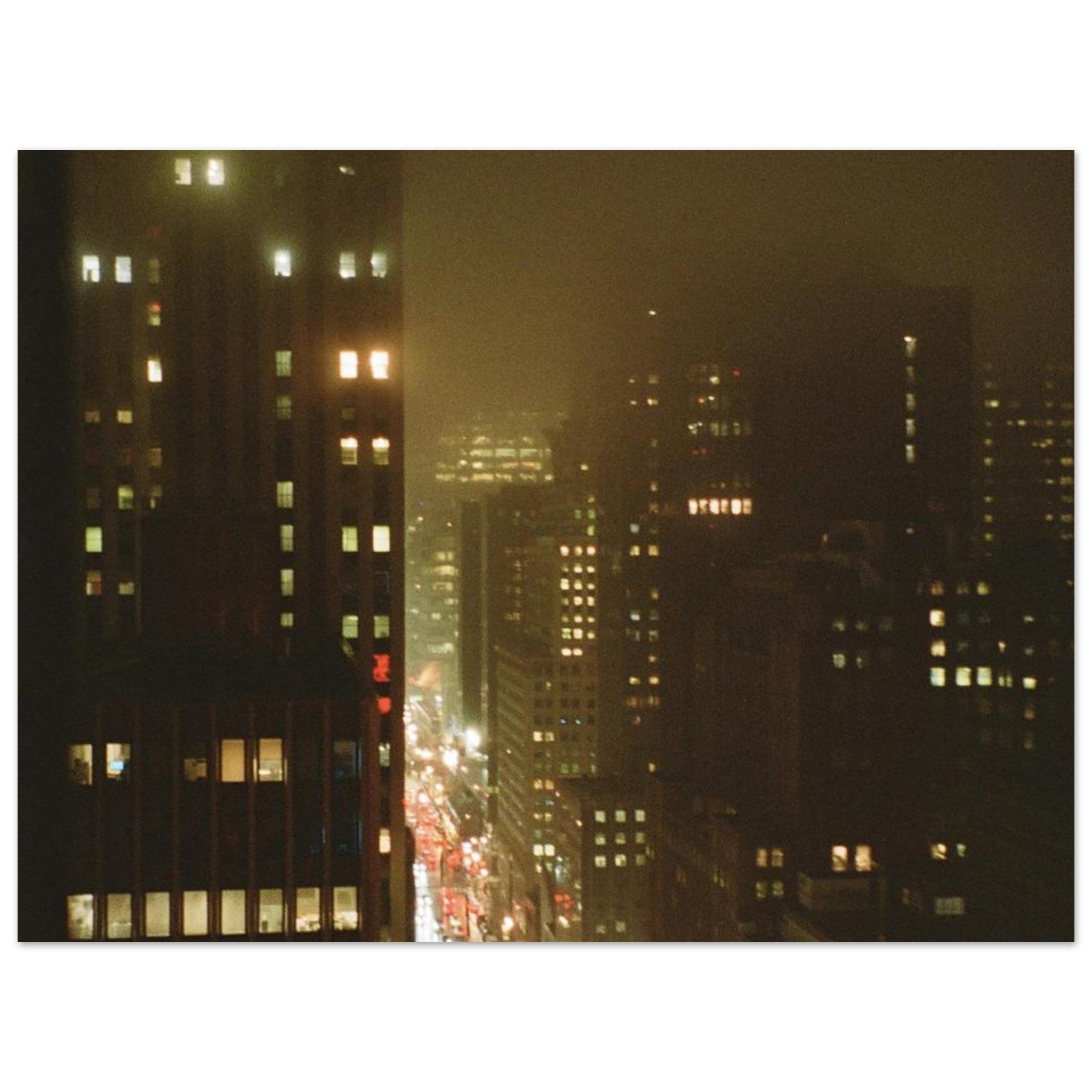 Film photo of wet city buildings at night across dark foggy streets