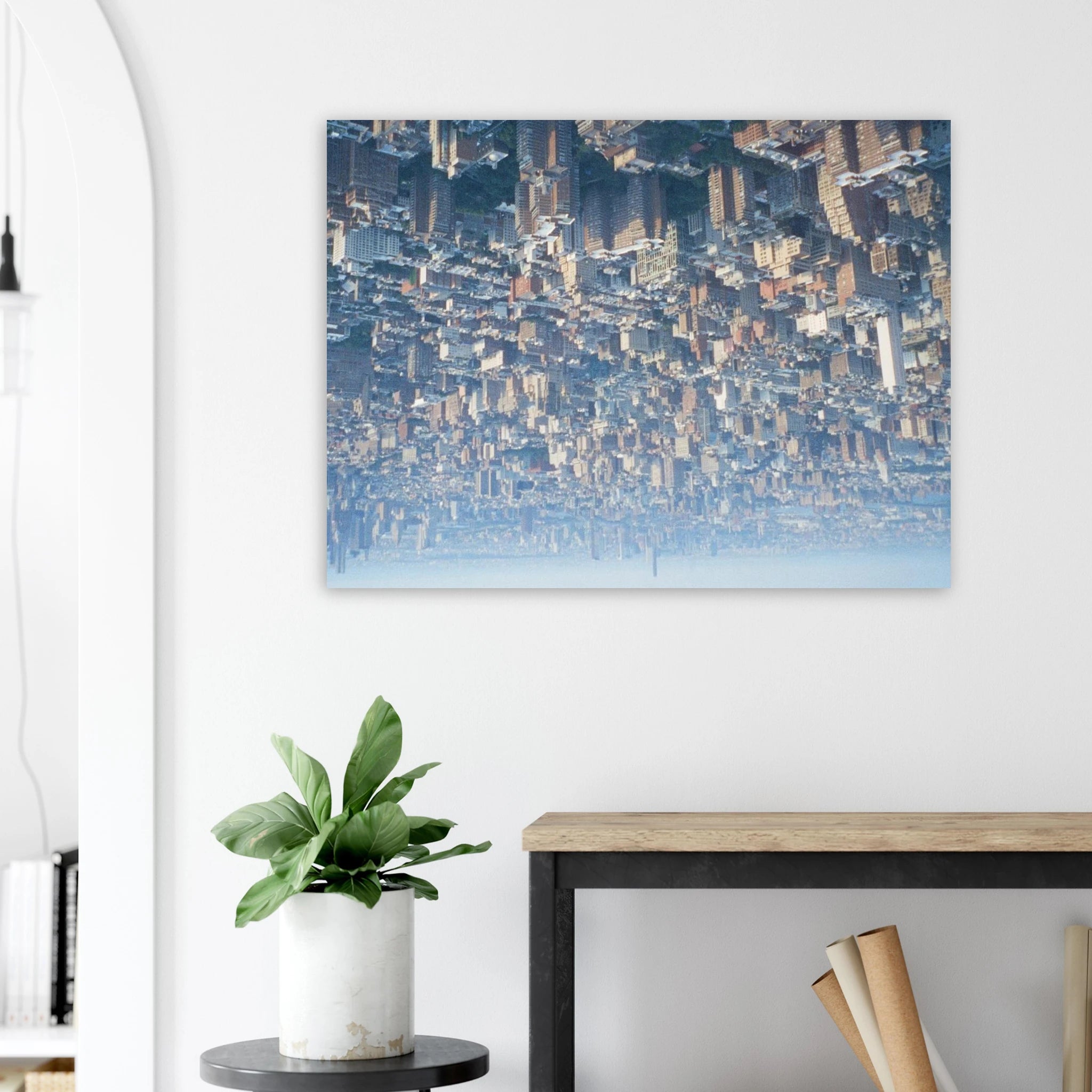 Cityscape painting on a wall above a desk with a plant