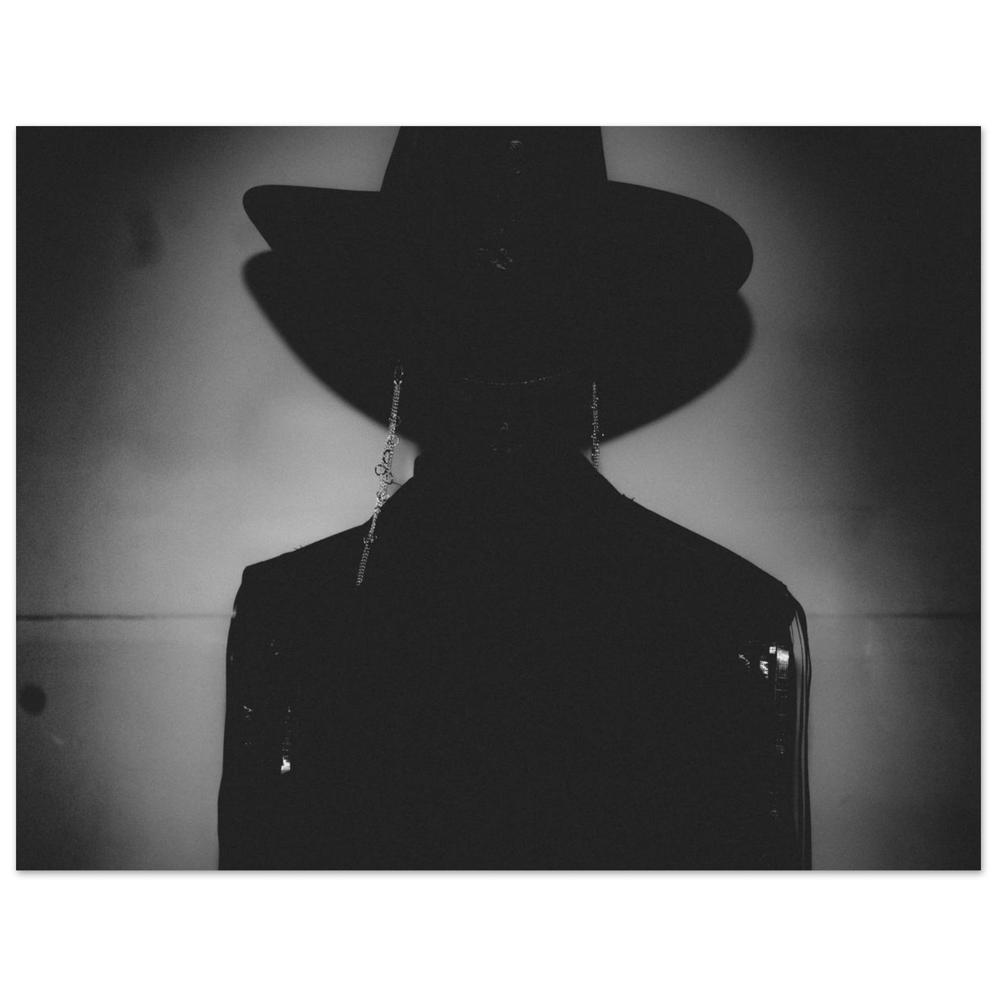 Black and white silhouette of a person wearing a hat against a plain background