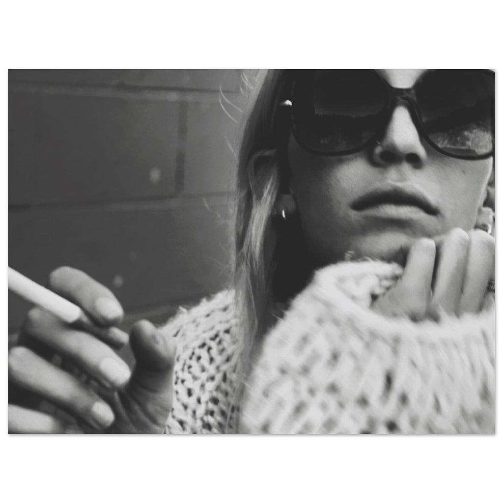 Black and white photo of a person wearing sunglasses and a textured garment, holding a cigarette.